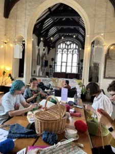 Tables inside a church with people sitting and kitting and crocheting