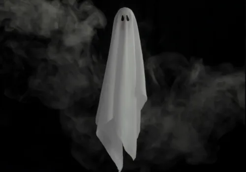 White sheet ghost with dark eyes floating in swirling smoke against a black background