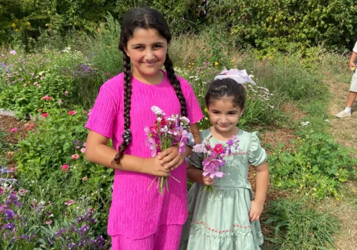 Two young people standing in front of a field with flowers